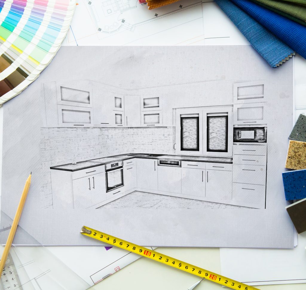 L-shaped kitchen design drawing surrounded by color swatches, a measuring tape, and a pencil.