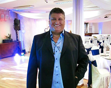 Man in a suit standing in a brightly lit reception venue.