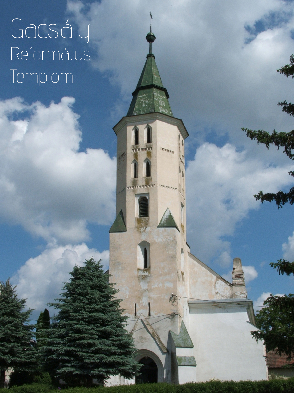 Weathered Gacsály Reformed Church tower with green spire against a cloudy blue sky.