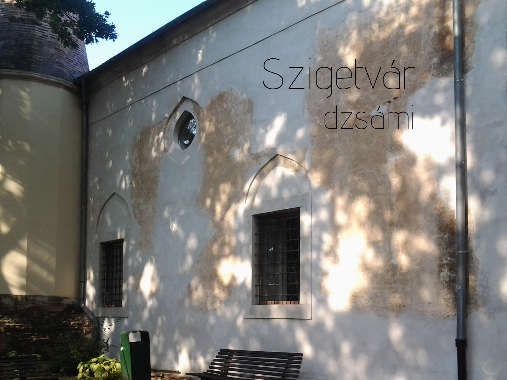 Weathered plaster wall of the Szigetvár mosque with pointed window surrounds and barred windows.