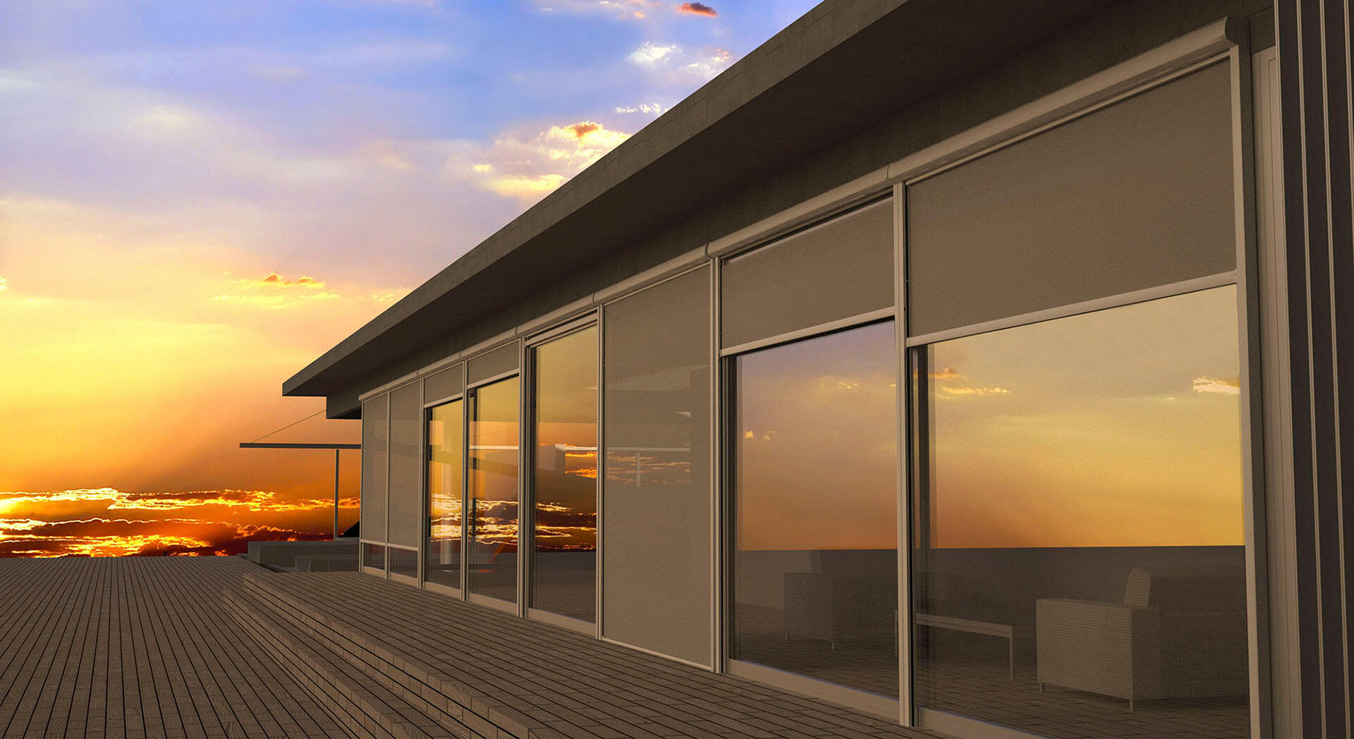 A modern flat-roofed building stands beside a broad wooden deck at sunset. Large glazed openings line the facade, with several gray fabric-like panels or screens covering portions of the windows. The panels are set at varied positions, and the glass reflects orange clouds and sky. Low outdoor furniture is faintly visible through the right-side glazing; no people or readable text appear.