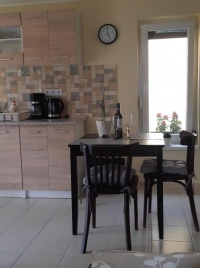Kis konyha étkezőasztallal és üvegajtóval a különálló apartmanban.