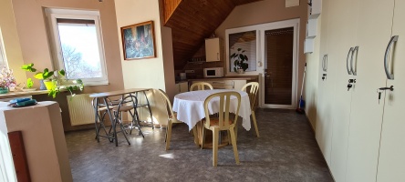 Közös étkező terített kerek asztallal és fa mennyezettel.