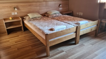 Két különálló fa ágy világos mintás ágyneművel egy fa falburkolatú szobában.