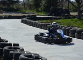 Go-kart driver on a tire-lined outdoor track.