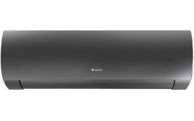 A charcoal-black wall-mounted split air-conditioning unit is isolated on a white background, seen straight on. Its casing has rounded ends and a narrow outlet seam along the bottom, with small white “GREE” branding near the center. A tiny dark mark appears toward the right side of the casing.
