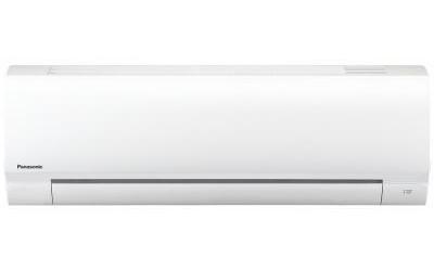 A white indoor air-conditioning unit is shown front-on against white. The casing is broad and flat, with a dark horizontal outlet opening low on the face; tiny “Panasonic” text appears at the left end. A small symbol near the lower right is too small to read.