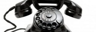 Black rotary dial telephone on a white background.