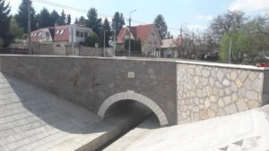 Felújított kőfalú híd íves nyílással.