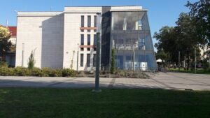 Világos homlokzatú épület fákkal
