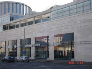 Magas üvegfalú épület világos oldalfallal