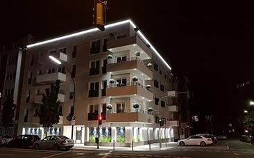 Kivilágított modern épület világos homlokzattal.