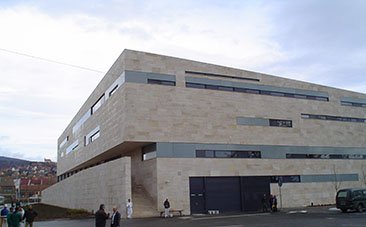 Letisztult modern épület világos homlokzatburkolattal.