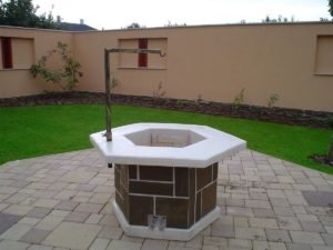 Nyolcszögletű kerti kút térburkolaton.