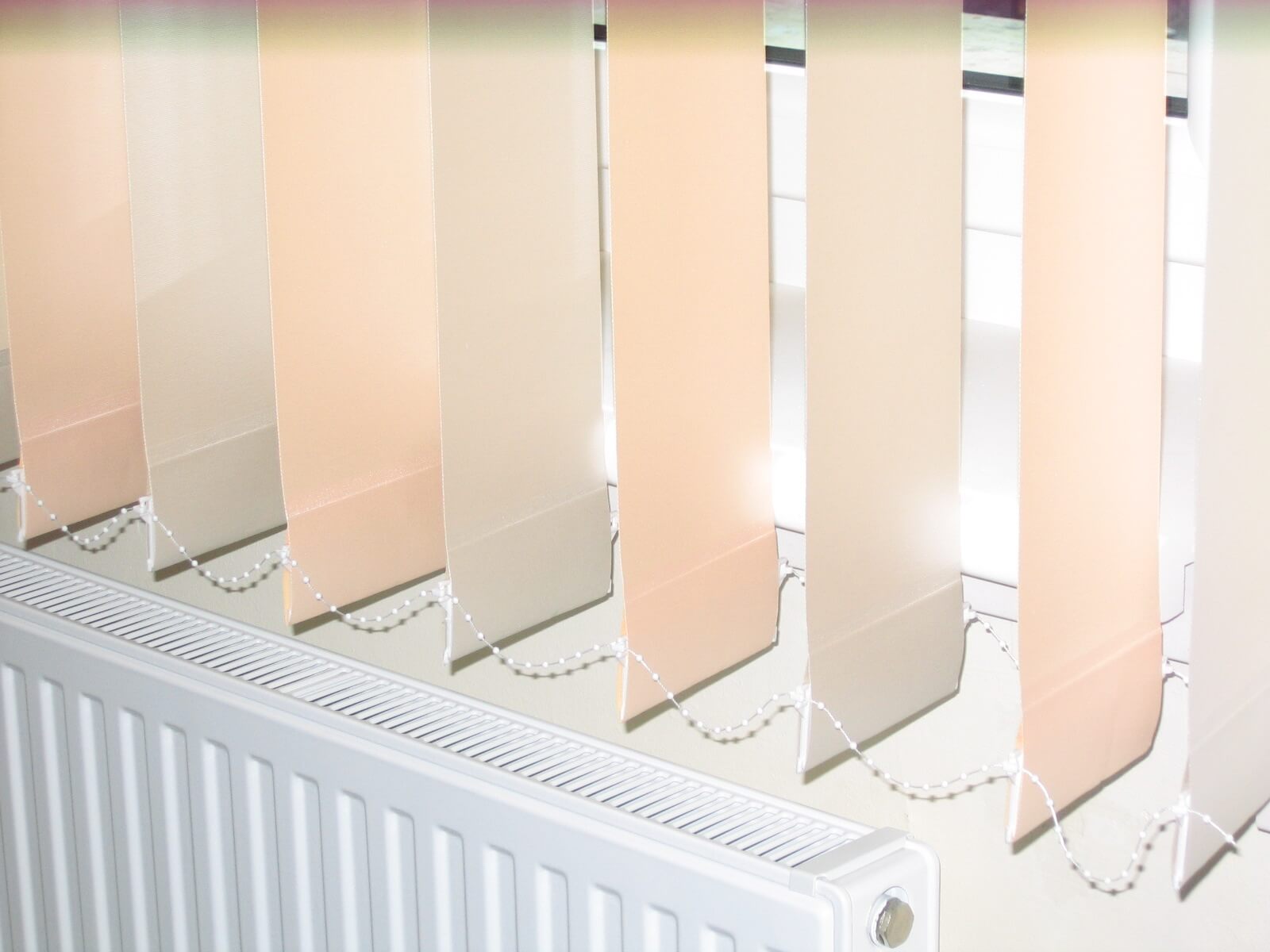 Beige vertical blinds above a white radiator.