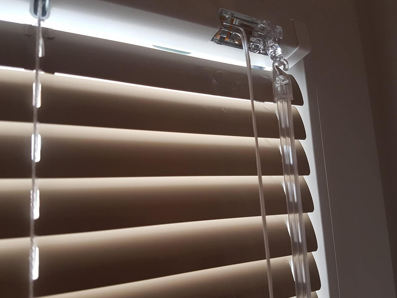Close-up of brown horizontal blinds and their operating cords.
