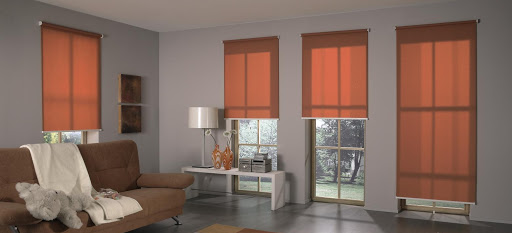 Living room with four orange roller shades over tall windows.