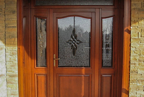 Ornate brown wood entrance door with frosted glass and sidelights.