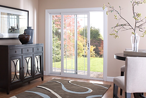Bright room with white sliding patio doors opening to a garden.
