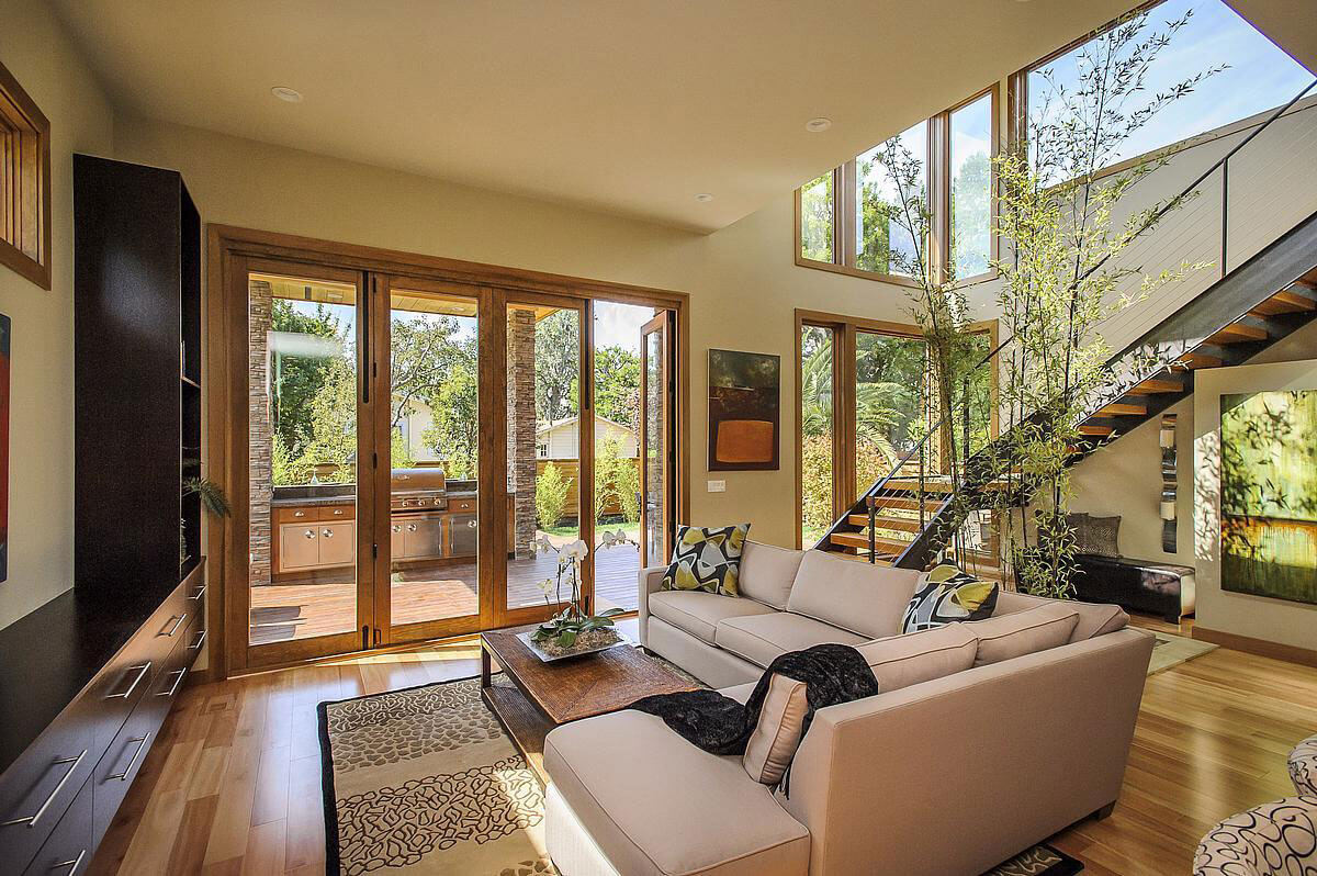 Warm living room with wood-framed glass doors and a staircase.