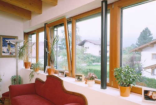 Wood-framed windows above a red sofa in a bright interior.