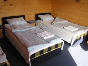 A faház belsejében két külön ágy, fa falak és napfényes ablak látható.
