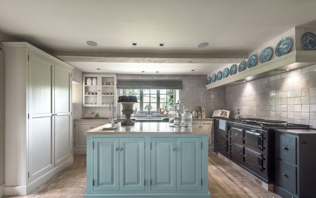 Pale blue island centered beneath a row of blue plates and tiled backsplash.