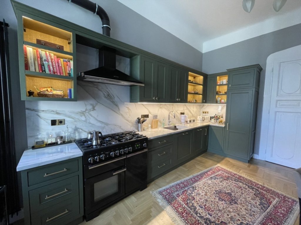 Charcoal cabinets, black range and patterned rug visible in a compact room.