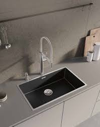 Dark rectangular sink and faucet set into a pale stone counter.