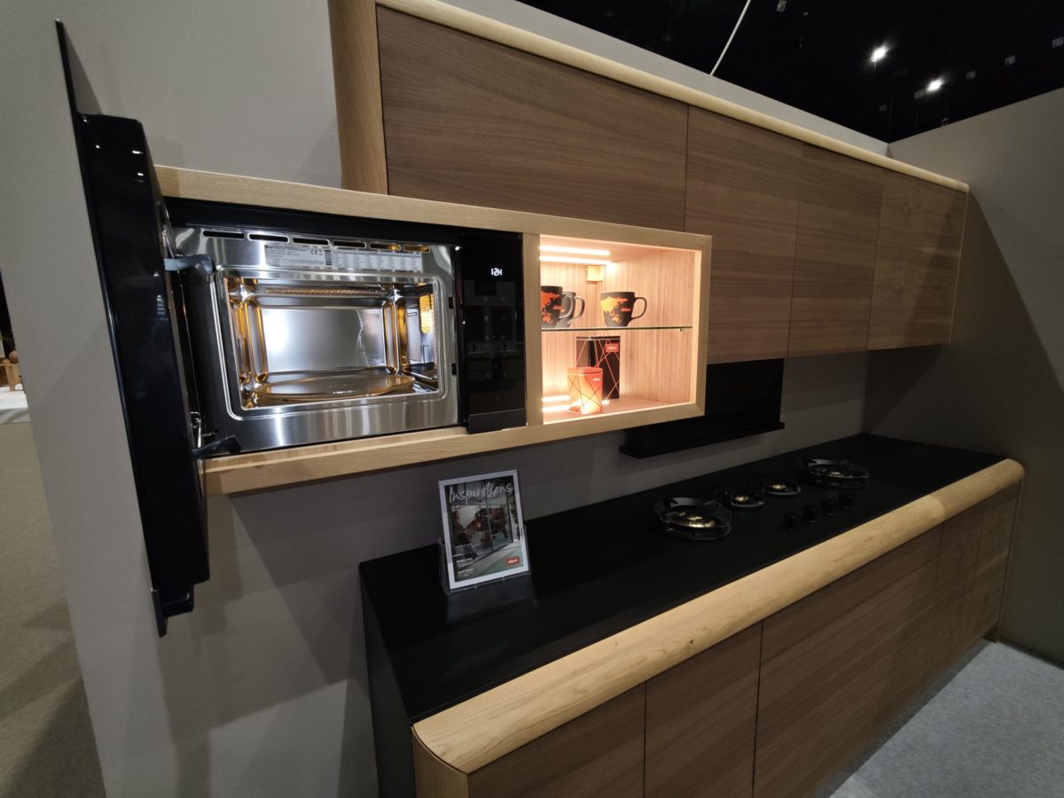 Dark wall unit with wood drawers, framed pictures and illuminated recess.