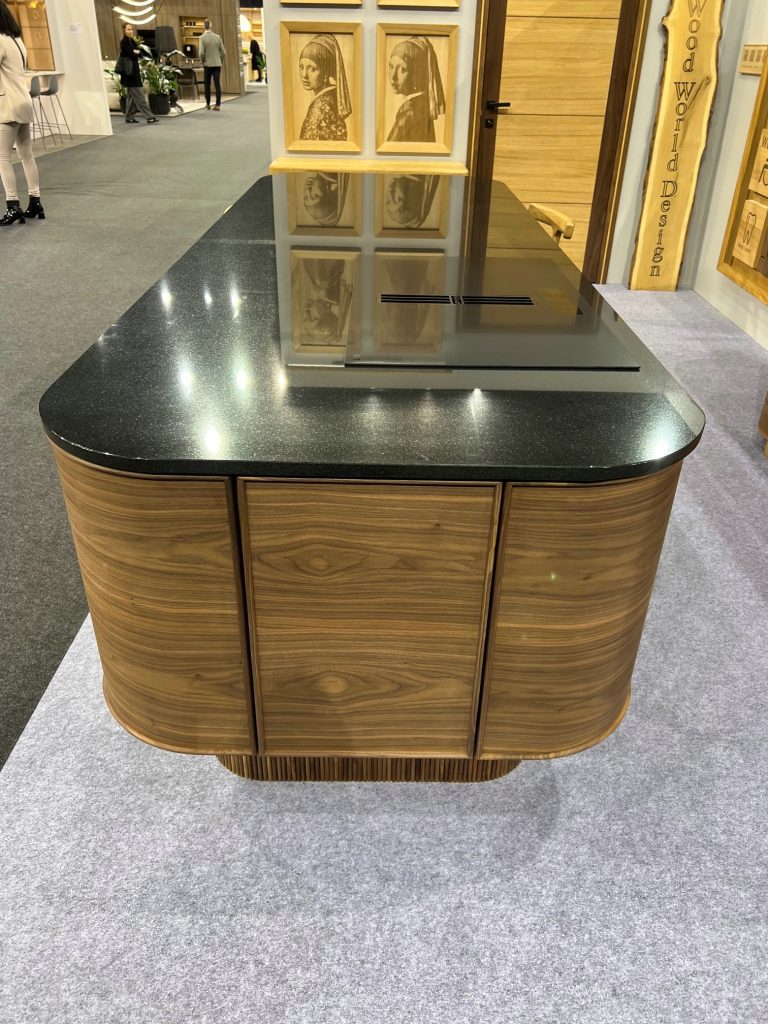 Front view of rounded wood island with sink and black top.