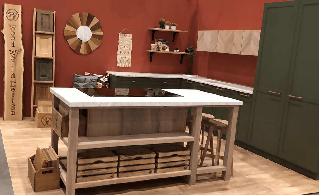 Green kitchen display with central island and patterned upper doors.
