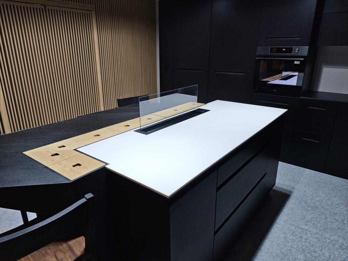 Large white worktop over a black island with wood drawer fronts.