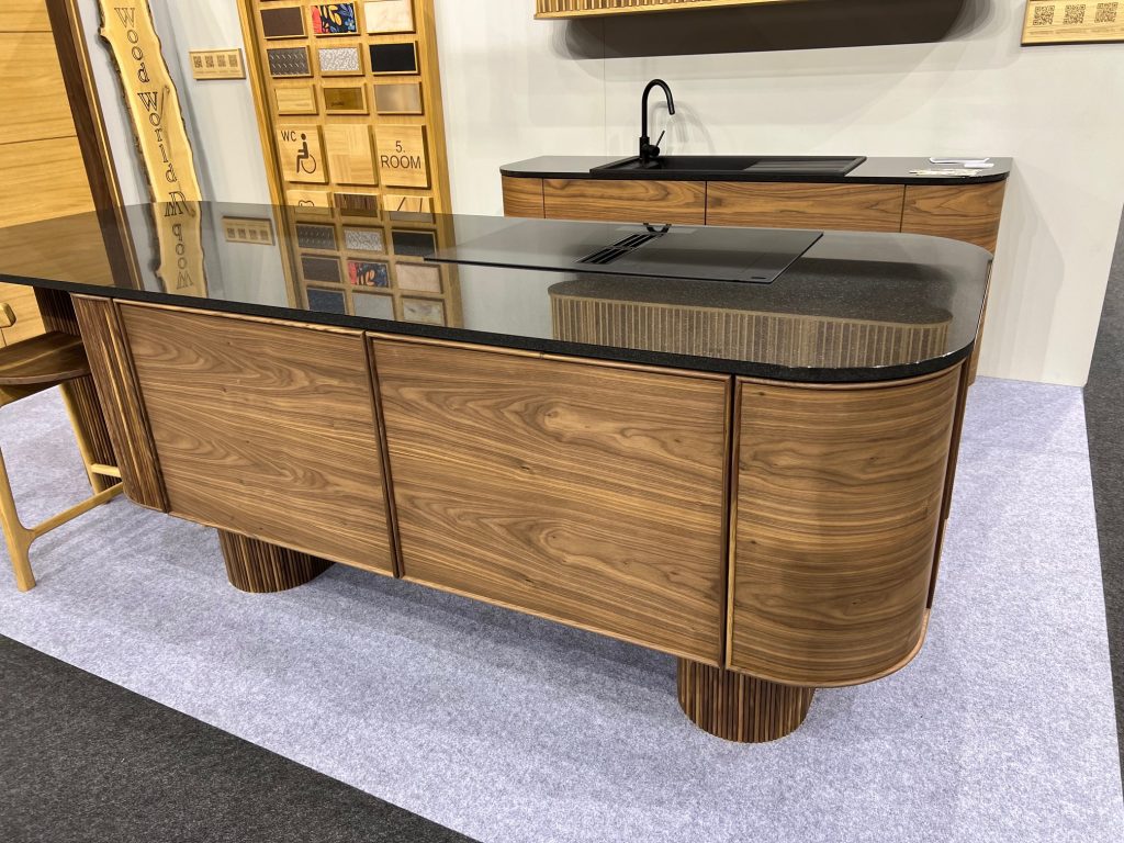 Long rounded wood cabinet run with black counter and pale wall.