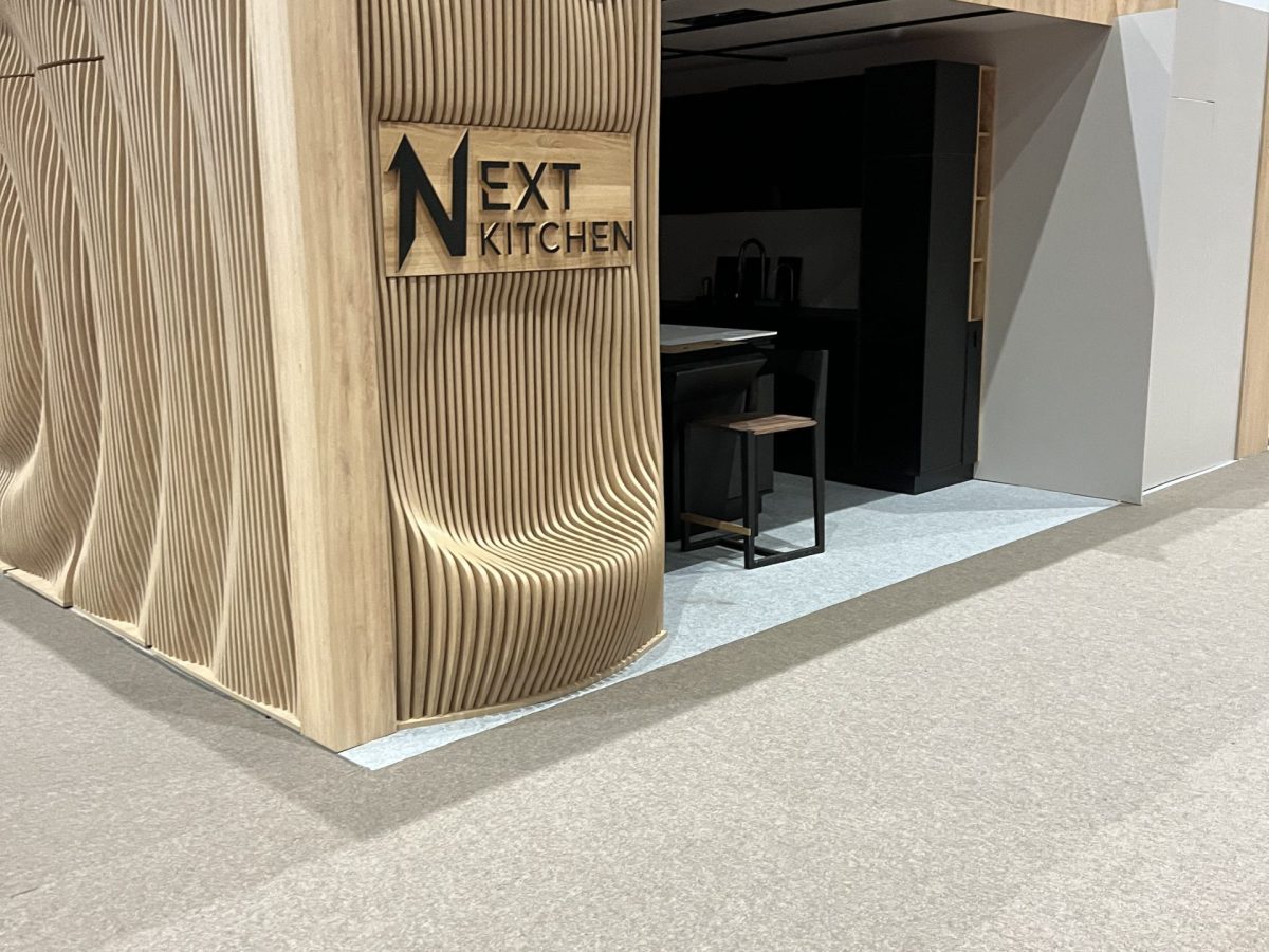 Sculpted pale wood display column with visible next kitchen text.
