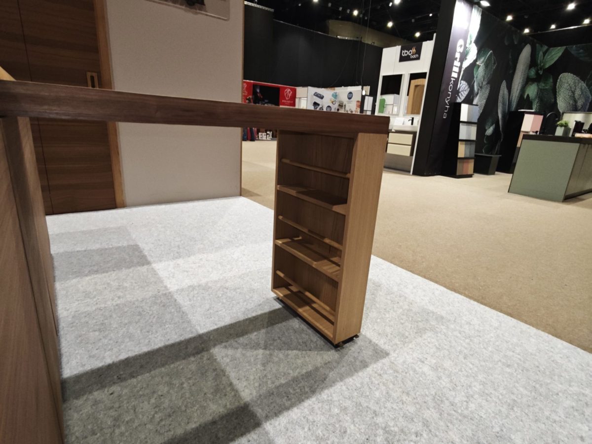 Small wood cabinet with open side shelving on a carpeted stand.