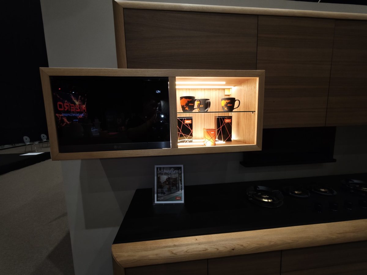 Wall-mounted wood storage with dark display screen and lit niche.