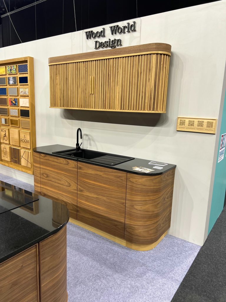 Wood display wall beside a rounded dark countertop and white wall.