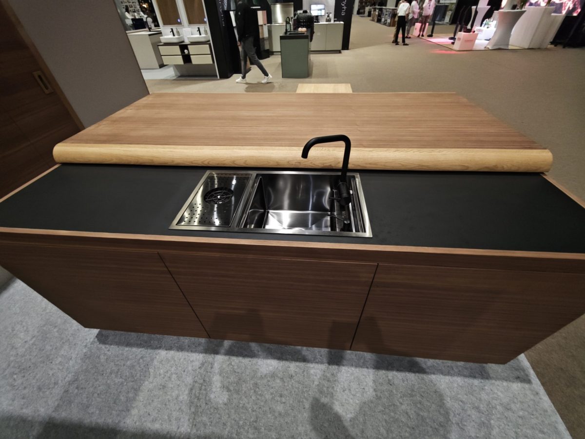 Wood island with stainless sink set into a dark countertop.
