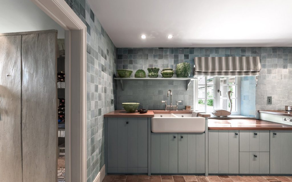 Gray slab-front kitchen with stone-look backsplash and striped window shade.