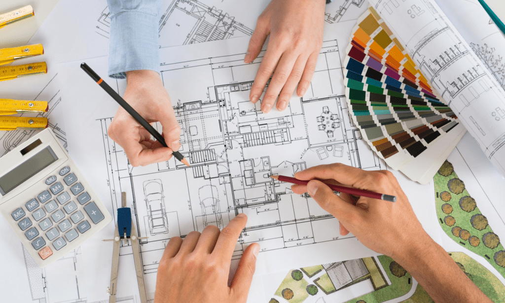 Hands arrange color samples and a kitchen drawing on a white planning table.