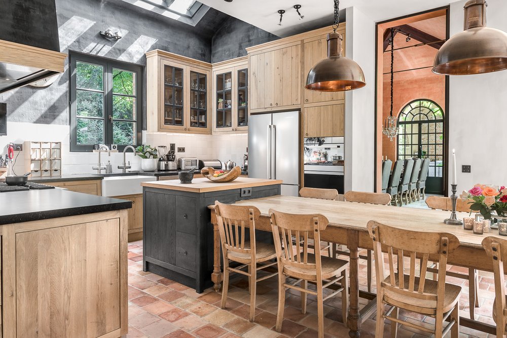 Loft kitchen with tall wood cabinets, large dining table and broad windows.
