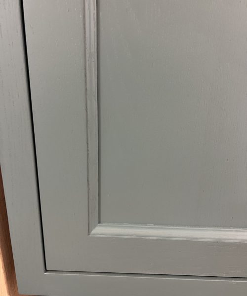 Pale gray framed cabinet panel.