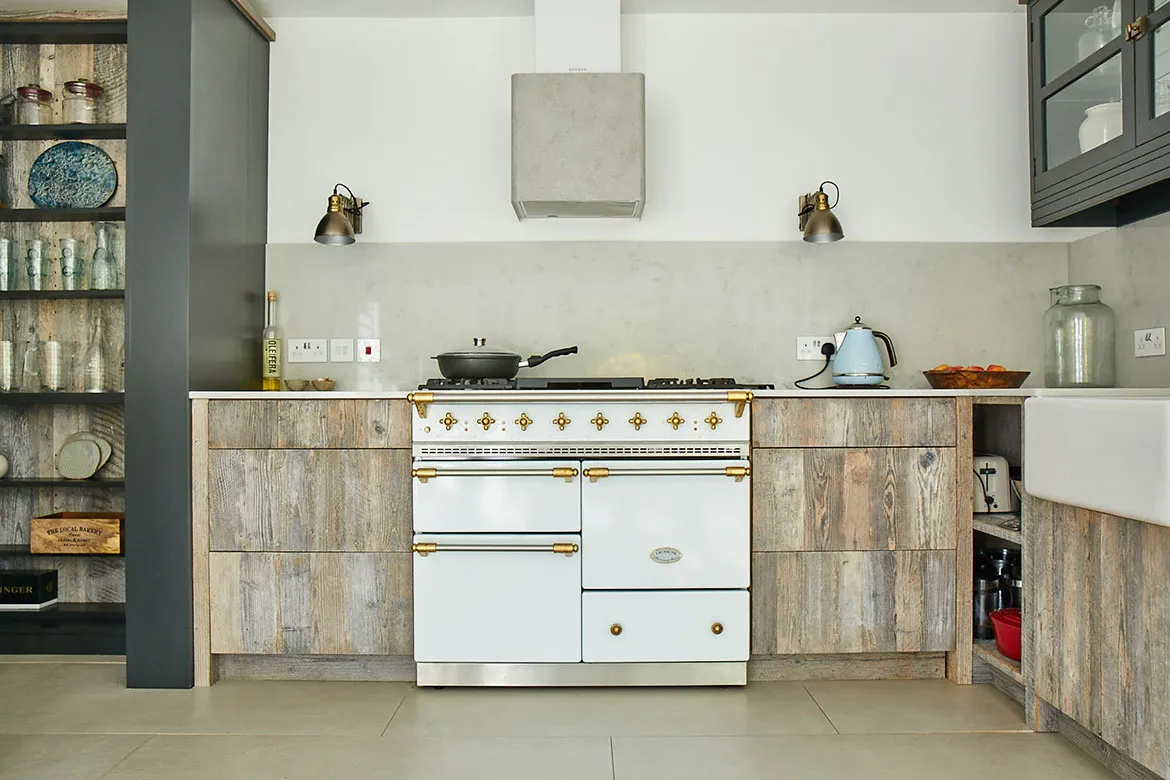 Pale kitchen with dark range and brass hood.