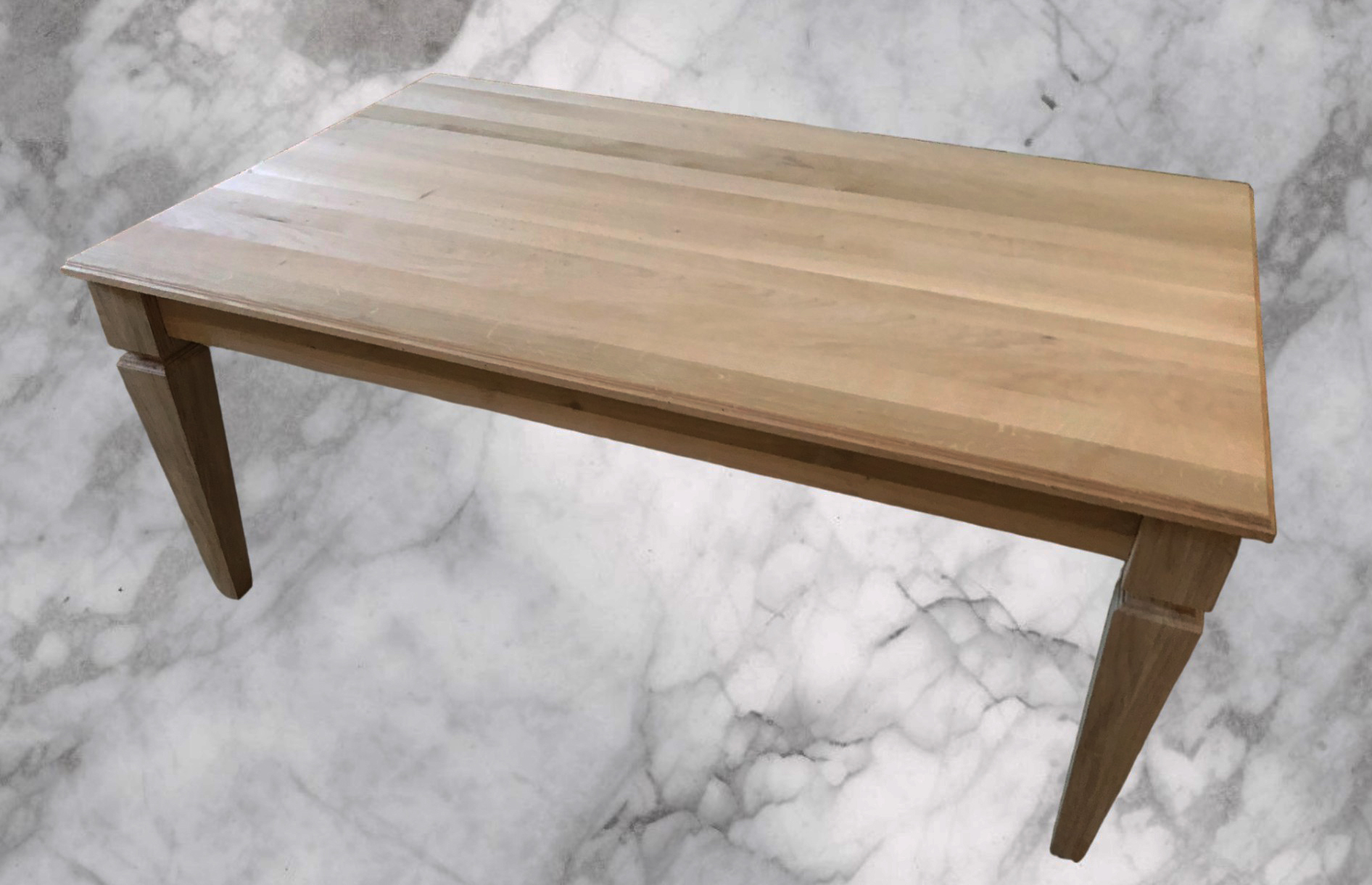 Close-up of a pale wood tabletop with pointed tapered legs.