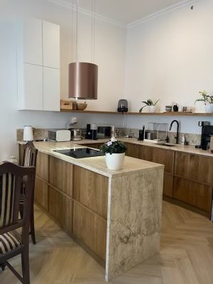 Pale wood island and white wall cabinets viewed from the dining side.