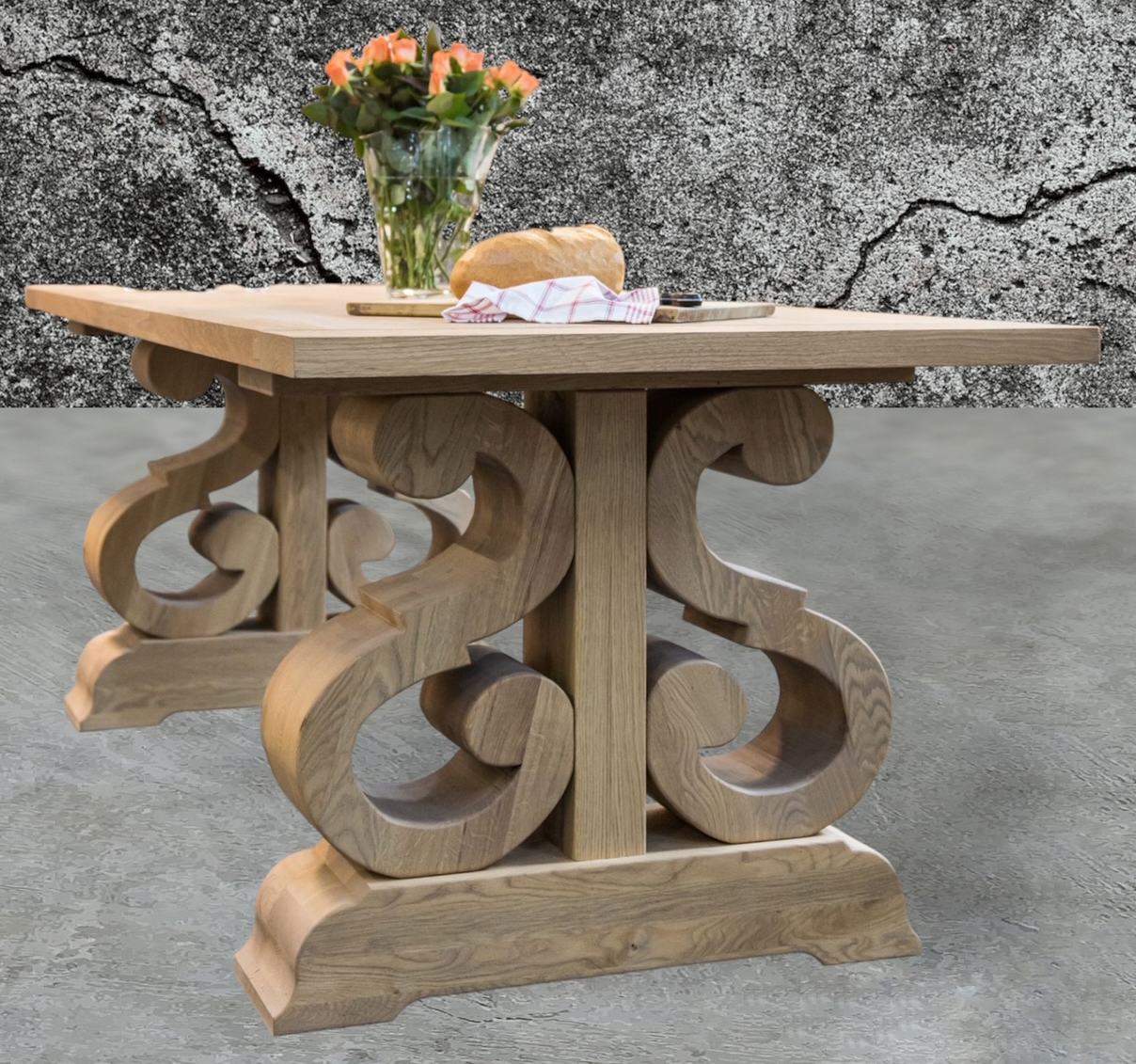 Small round-topped table with ornate carved scroll base against a stone wall.