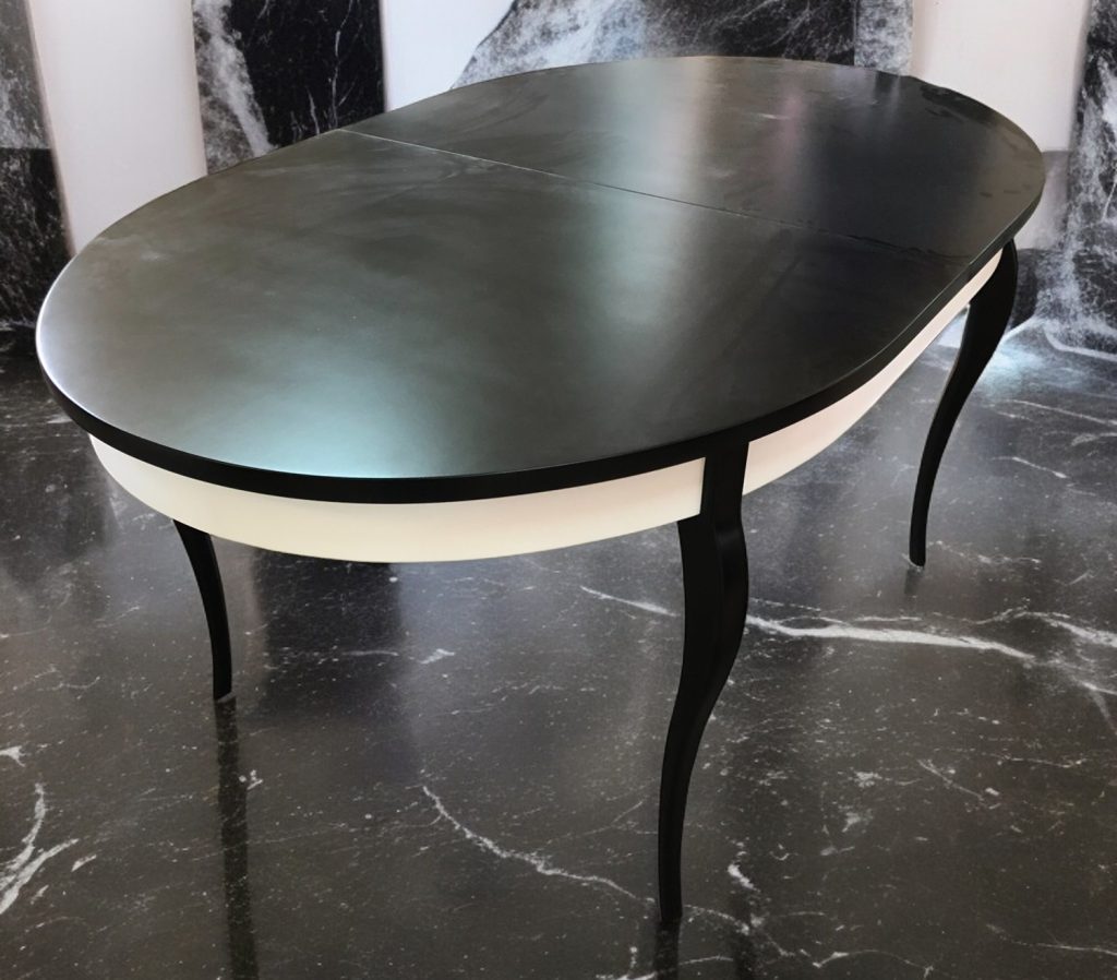 Rounded black table with slender legs.
