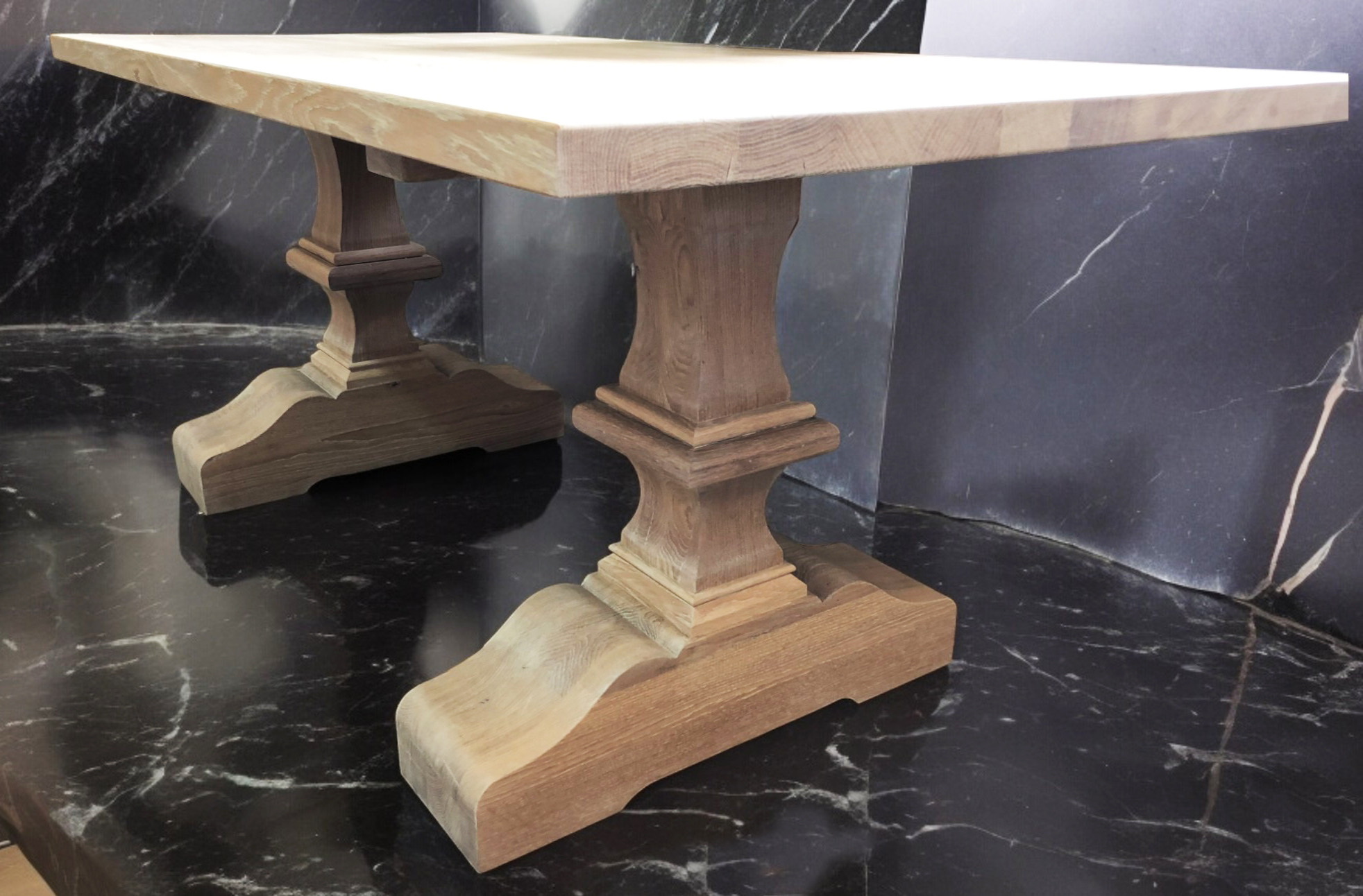 Light tabletop on two square stepped pedestal blocks over a dark floor.