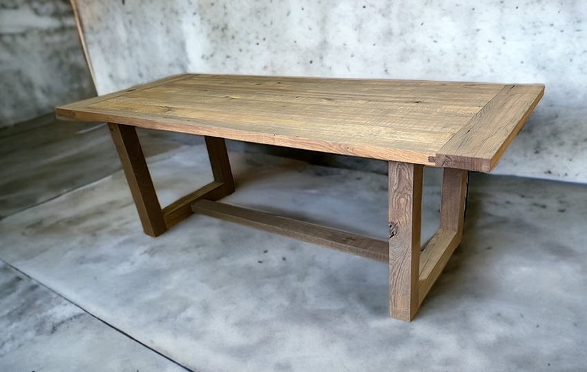Thick tabletop on rectangular block legs and a low dark stretcher.